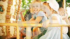 Happy little girls ride a retro carousel on a sunny summer day in Grenoble, France