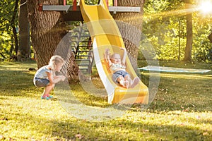 Happy little girls rolling down the hill on the playground