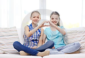 Happy little girls showing heart shape hand sign