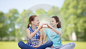 Happy little girls showing heart shape hand sign