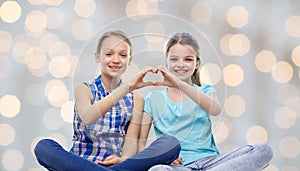 Happy little girls showing heart shape hand sign