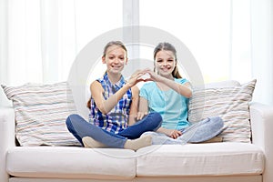 Happy little girls showing heart shape hand sign