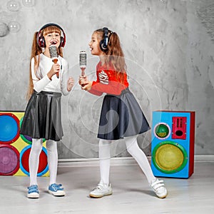 Happy little girls sing and listen to music in headphones. The c