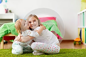 Happy little girls or sisters hugging at home