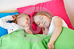 Happy little girls sleeping in bed at home