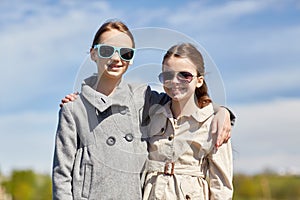 Happy little girls in sunglasses hugging outdoors