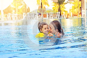 Happy little girls swimming in outdoor pool at sunset. Toned