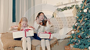 Happy little girls who received Christmas presents. Two small children are happy with gifts in boxes.