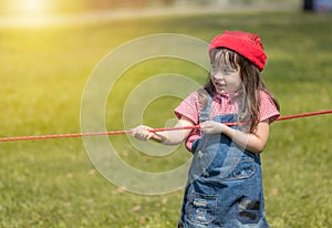 Happy little gril playing rope tug of war in park photo