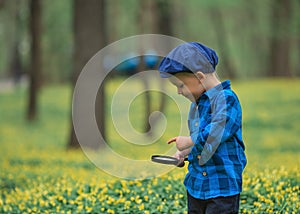 Happy little happy child boy, exploring nature with magnifying glass, summer. Concept of kid and nature