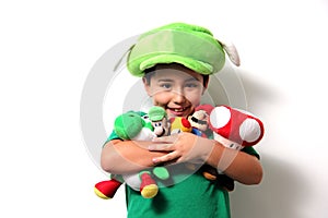 Happy little Hispanic boy hugs all his stuffed animals that are his favorite toys to play with his stuffed hat that he got for his