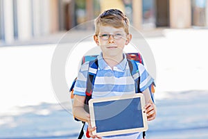 Happy little kid boy with backpack or satchel and glasses. Schoolkid on the way to school. Healthy adorable child