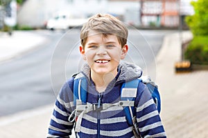 Happy little kid boy with backpack or satchel. Schoolkid on way to elementary school. Healthy adorable child outdoors