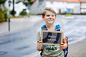 Happy little kid boy with backpack or satchel. Schoolkid on the way to middle or high school. Child outdoors on the
