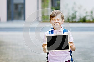 Happy little kid boy with backpack or satchel. Schoolkid on the way to school. Healthy adorable child outdoors With