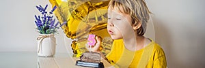 Happy little kid boy celebrating his birthday and blowing candles on homemade baked cake, indoor. Birthday party for