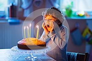 Little kid boy celebrating his birthday and blowing candles on cake