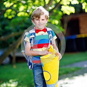 Happy little kid boy in colorful shirt and backpack or satchel and traditional German school bag called Schultuete on