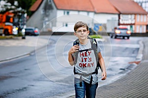 Happy little kid boy with glasses and backpack or satchel. Schoolkid on the way to middle or high school. Healthy