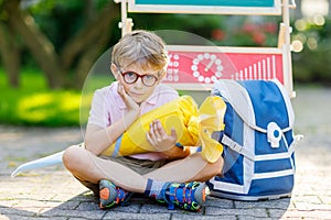 Šťastný malý dítě chlapec brýle podle psací stůl a batoh nebo aktovka. tradiční nemec taška 