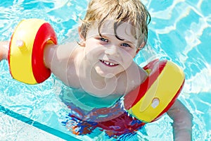 Happy little kid boy having fun in an swimming pool