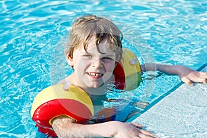 Happy little kid boy having fun in an swimming pool