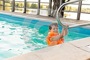Happy little kid boy having fun in an swimming pool. Active happy preschool child learning to swim.