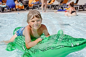 Happy little kid boy jumping in the pool and having fun on family vacations in a hotel resort. Healthy child playing in