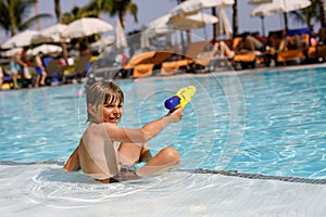 Happy little kid boy jumping in the pool and having fun on family vacations in a hotel resort. Healthy child playing in