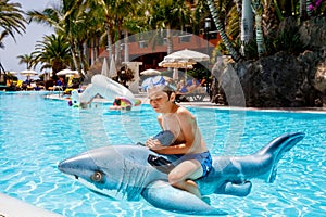 Happy little kid boy jumping in the pool and having fun on family vacations in a hotel resort. Healthy child playing in