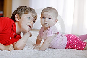 Happy little kid boy with newborn baby girl, cute sister. Siblings. Brother and baby playing together