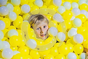 Happy little kid boy playing at colorful plastic balls playground high view. Adorable child having fun indoors