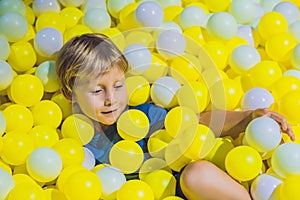 Happy little kid boy playing at colorful plastic balls playground high view. Adorable child having fun indoors