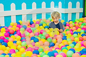 Happy little kid boy playing at colorful plastic balls playground high view. Funny child having fun indoors