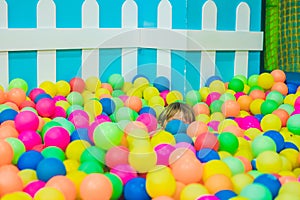 Happy little kid boy playing at colorful plastic balls playground high view. Funny child having fun indoors