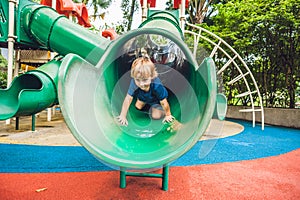 Happy little kid boy playing at colorful playground. Adorable child having fun outdoors