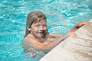 Happy little kid boy playing with in outdoor swimming pool on hot summer day. Kids learn to swim. Family beach vacation