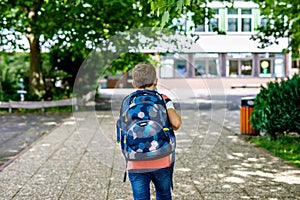 Happy little kid boy with satchel. Schoolkid on the way to middle or high school. Healthy adorable child outdoors on
