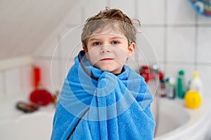 Happy little kid boy after taking bath with blue towel