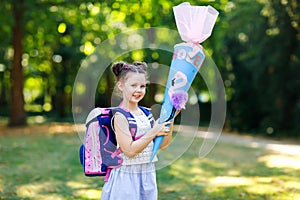 Happy little kid girl with backpack or satchel and big school bag or cone traditional in Germany for the first day of