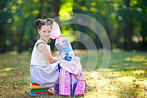 Happy little kid girl with backpack or satchel, books and big school bag or cone traditional in Germany for the first