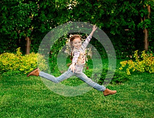 Happy little kid girl jumping on the summer meadow