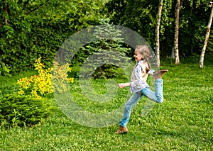 Happy little kid girl jumping on the summer meadow