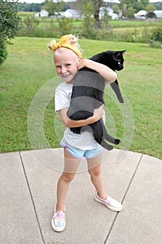 Happy little Kid Holding her Pet Black Cat Outside