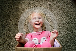 Happy Little Kid Laughing as she Plays in Cardboard Box at her Home