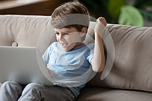Happy little kid play game on modern laptop