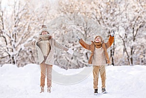 Happy little kids brother and sister rejoicing first snow in snowy winter park