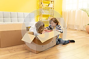 Happy little kids children enjoying moving day, playing in new home together, preschool boy and 8s girl having fun with