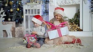 Happy little kids opening presents on Xmas eve. Children under Christmas tree with gift boxes. Decorated living room with