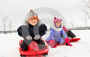 Happy little kids sliding down on sleds in winter